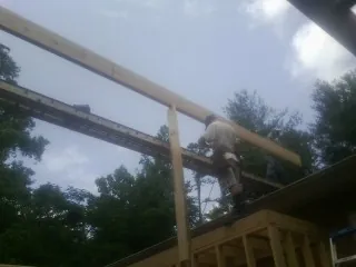 Carpenter setting a ridge beam over a new addition frame — Ice Dam Removal by Roofing Brothers in Glendo