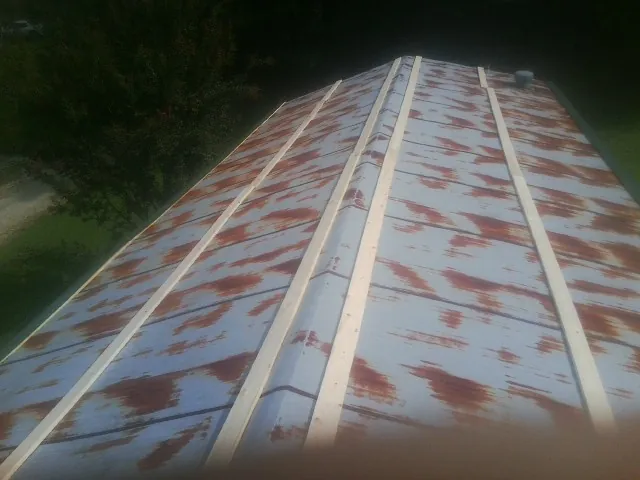 Rusted metal roof panels with new wood purlins before replacement — Storm Damage Roof Repair in Glendo by Roofing Brothers