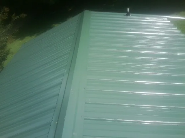 New green metal panels meeting at the ridge of a roof — Flat Roof Repair work by our crew in Glendo
