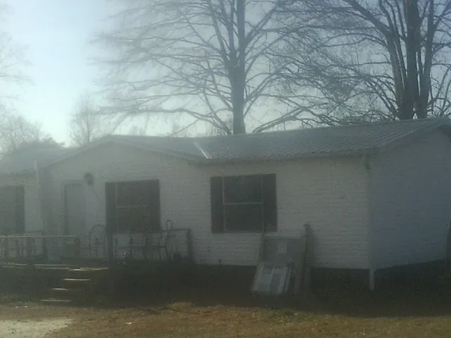 New metal roof on a white painted brick home on a foggy morning in Glendo