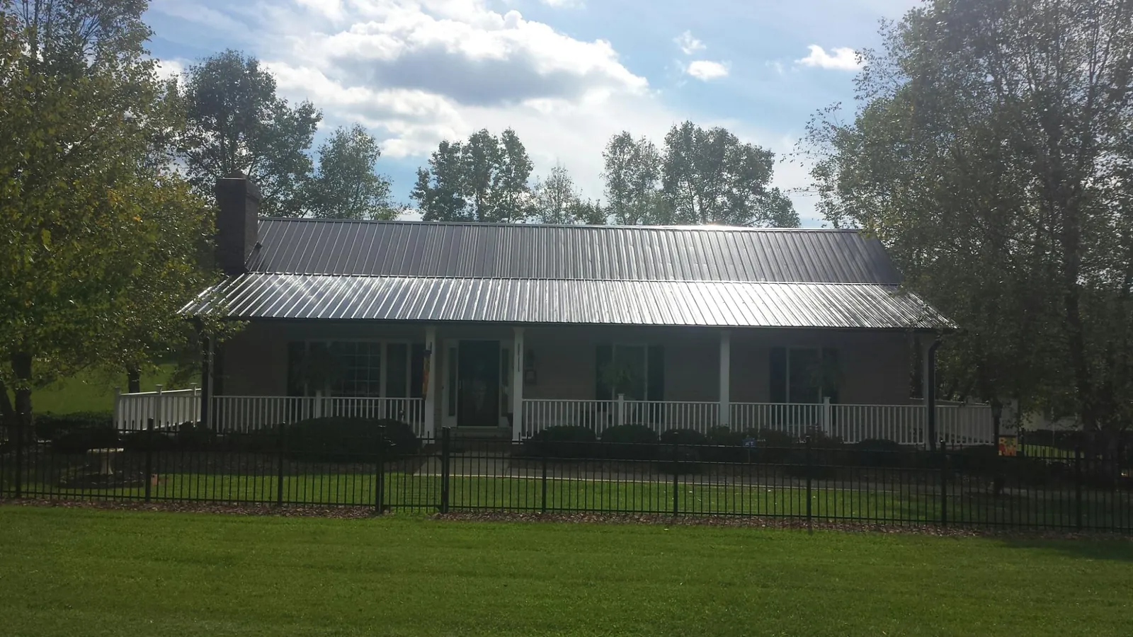 Gray metal roof on a brick ranch with a full width front porch — Gutter Guard Installation work by our crew in Glendo
