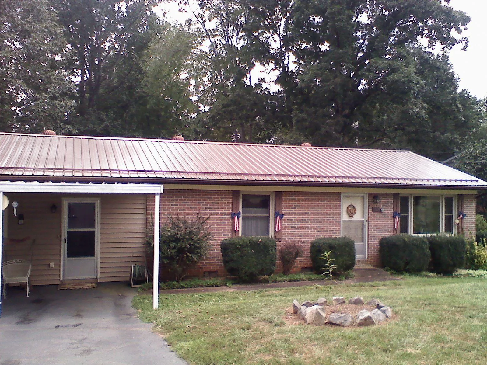 Bronze metal roof and carport on a brick ranch home — Roof Repair work by our crew in Glendo