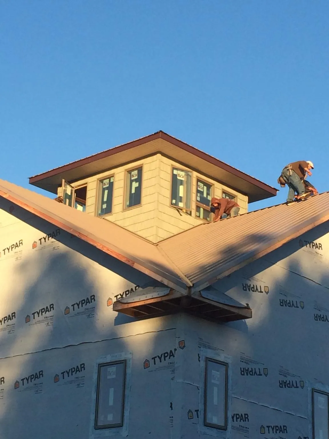 Roofers working around a rooftop cupola on a new metal roof at sunset — Roof Waterproofing in Glendo by Roofing Brothers